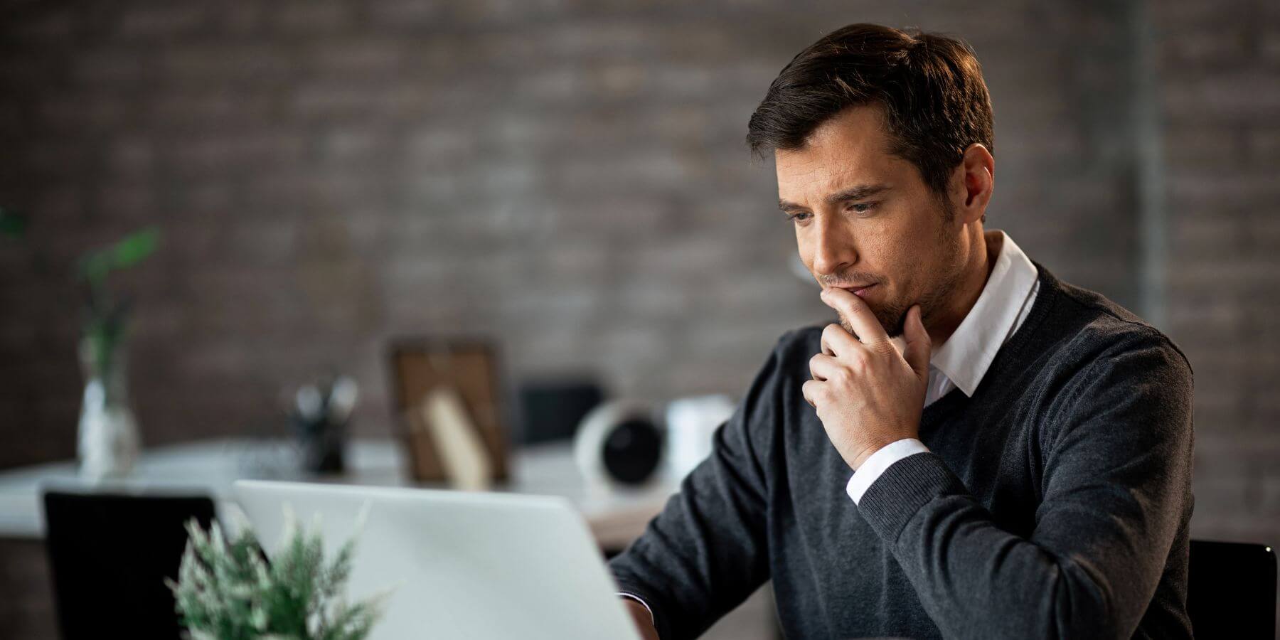 A man looking curiously at a laptop screen