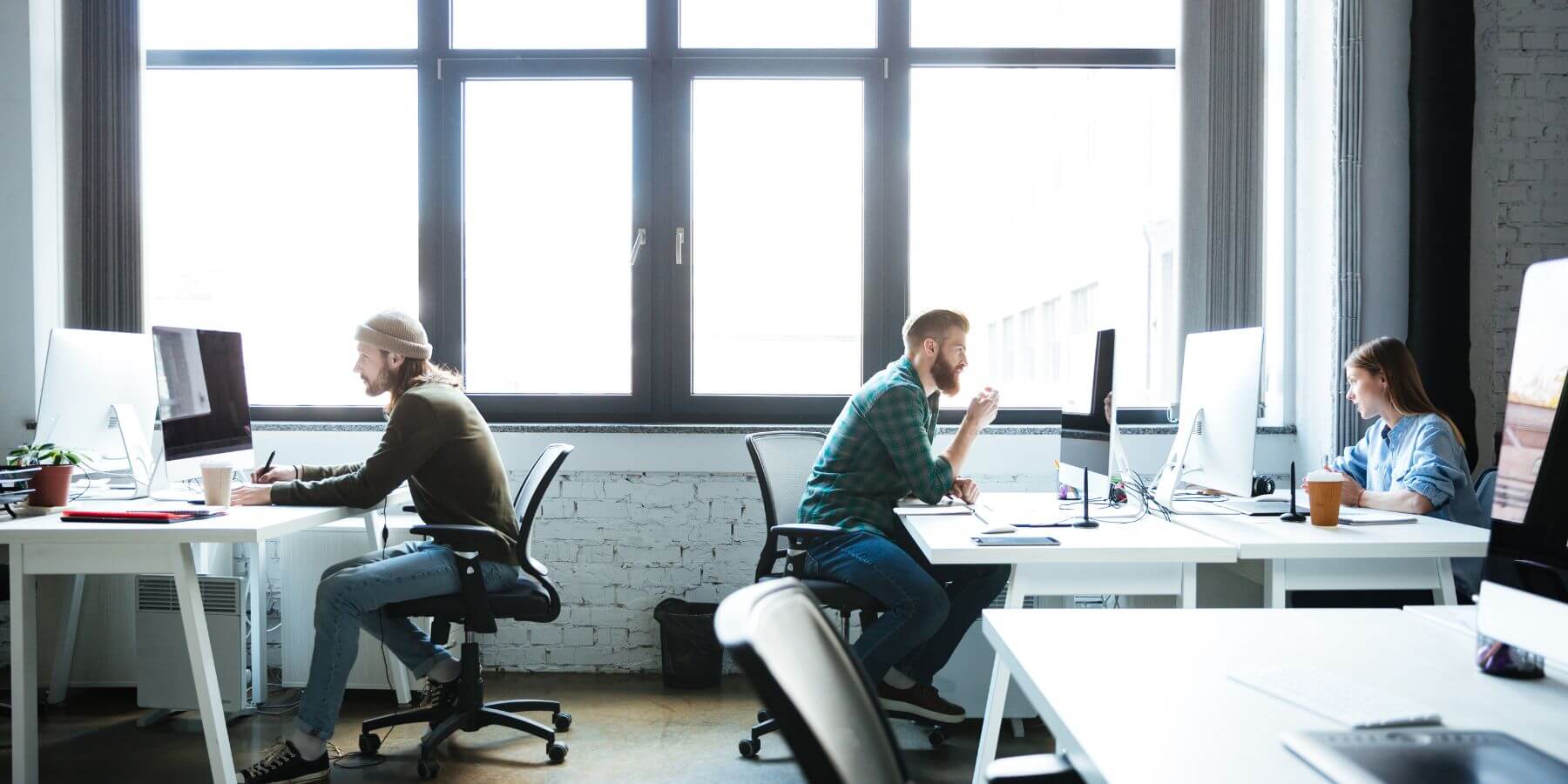 ree individuals working independently at their desks, each using a computer, in an office setting