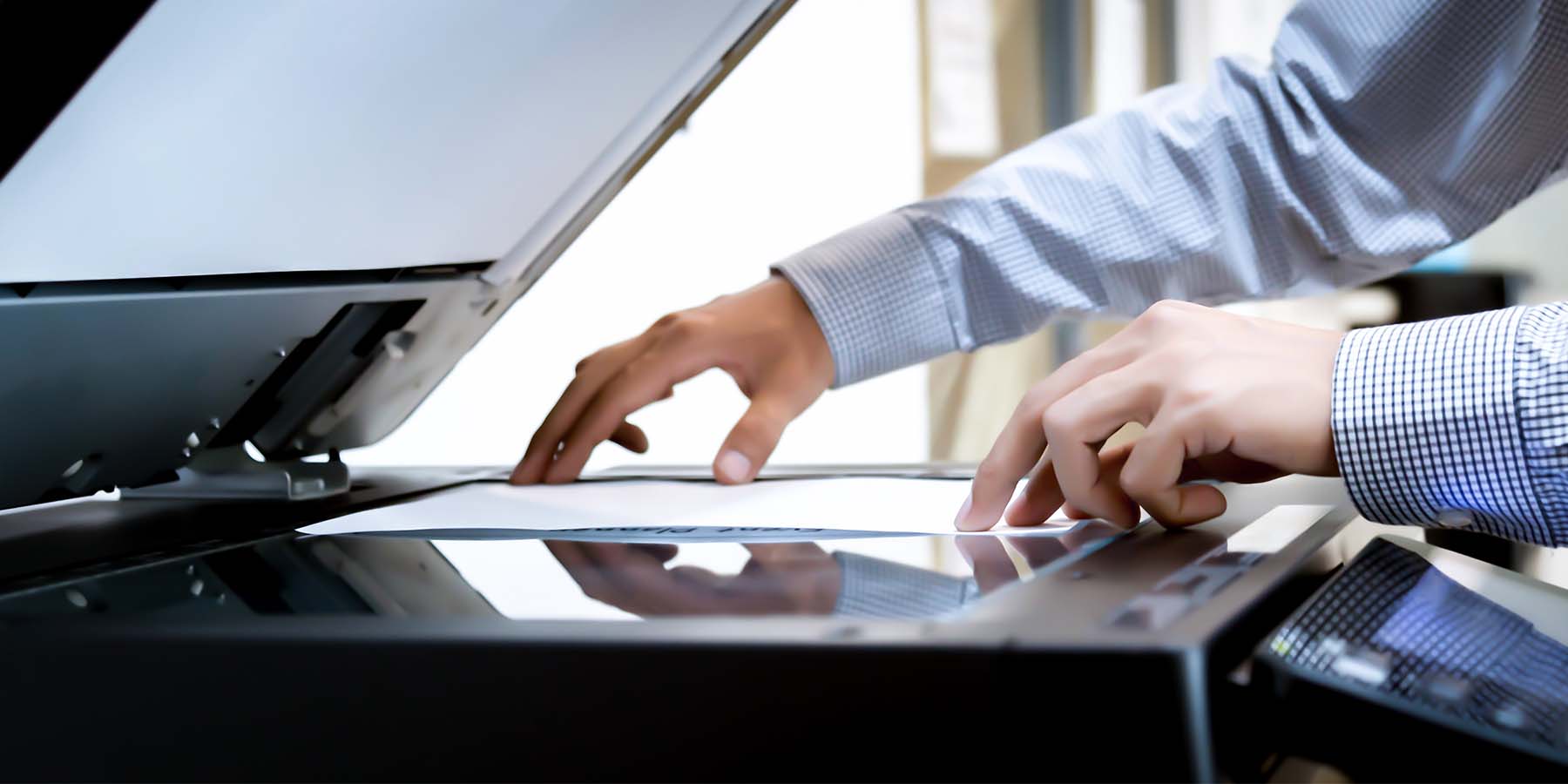 Hands of a man in a suit scanning a document on a printer
