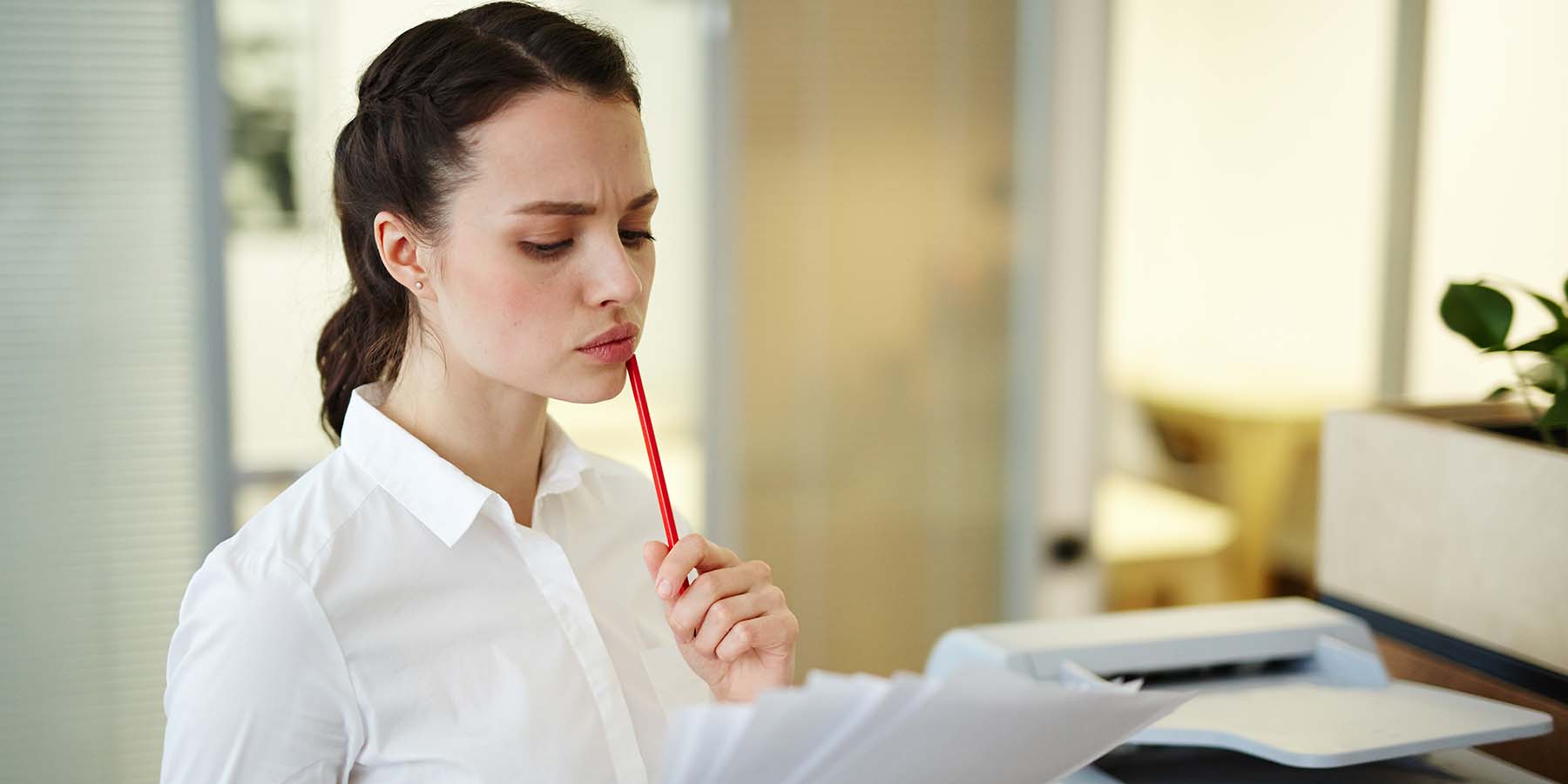 Women standing at printer reading a contract pensively