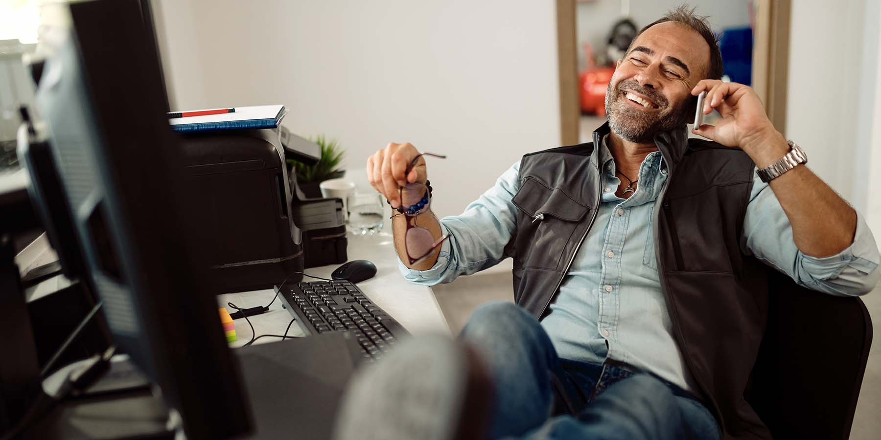 IT manager sitting at desk on the phone looking relaxed and smiling.