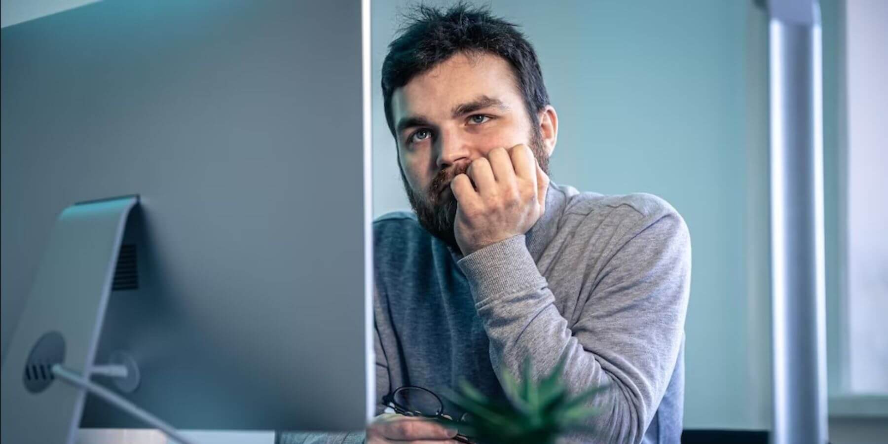 A photo of a professional man looking at his computer in exasperation.
