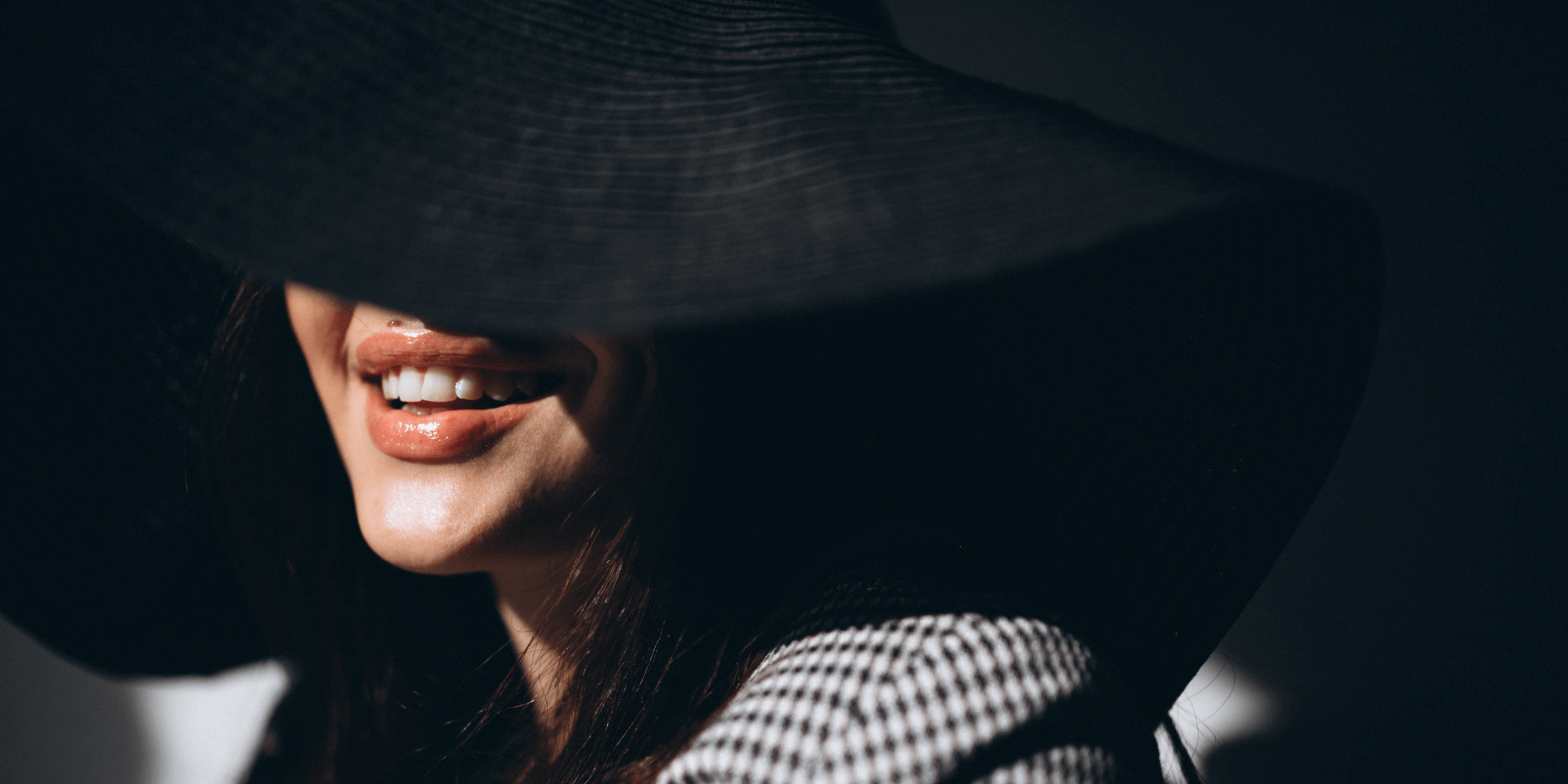 A woman, face obscured by shadow, smiling.