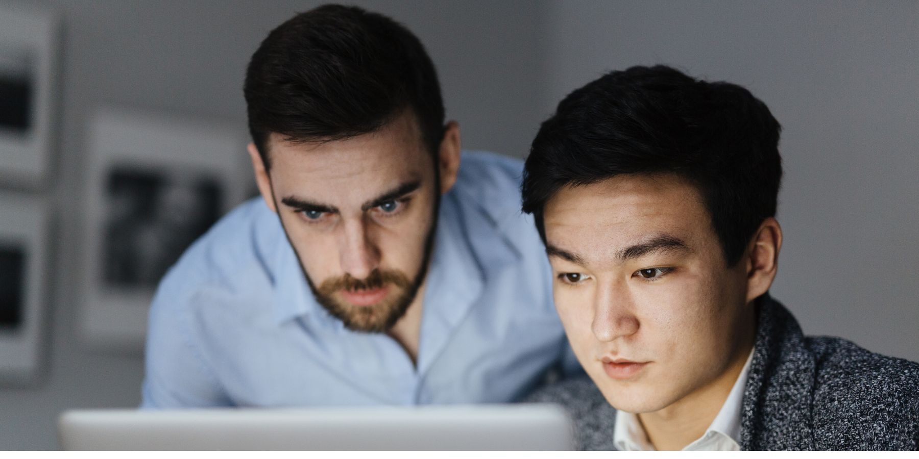 Two men looking sternly at the computer screen.