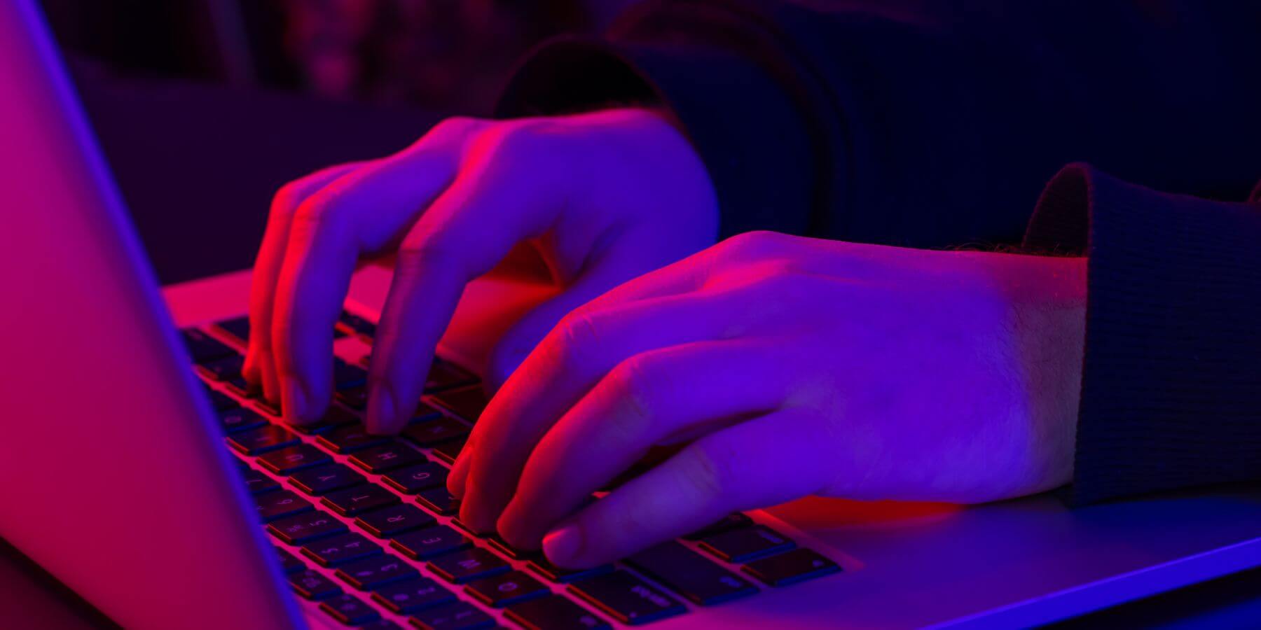 Two hands typing on a laptop keyboard.