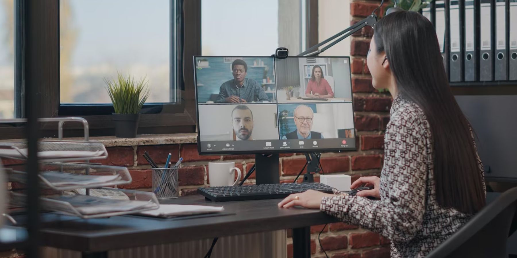  A woman in an office setting, actively participating in a video conference call with her colleagues.